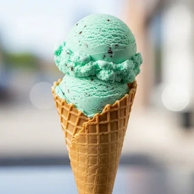 Casquinha com duas bolas de sorvete de menta com pedacinhos de chocolate. Fundo difuso.